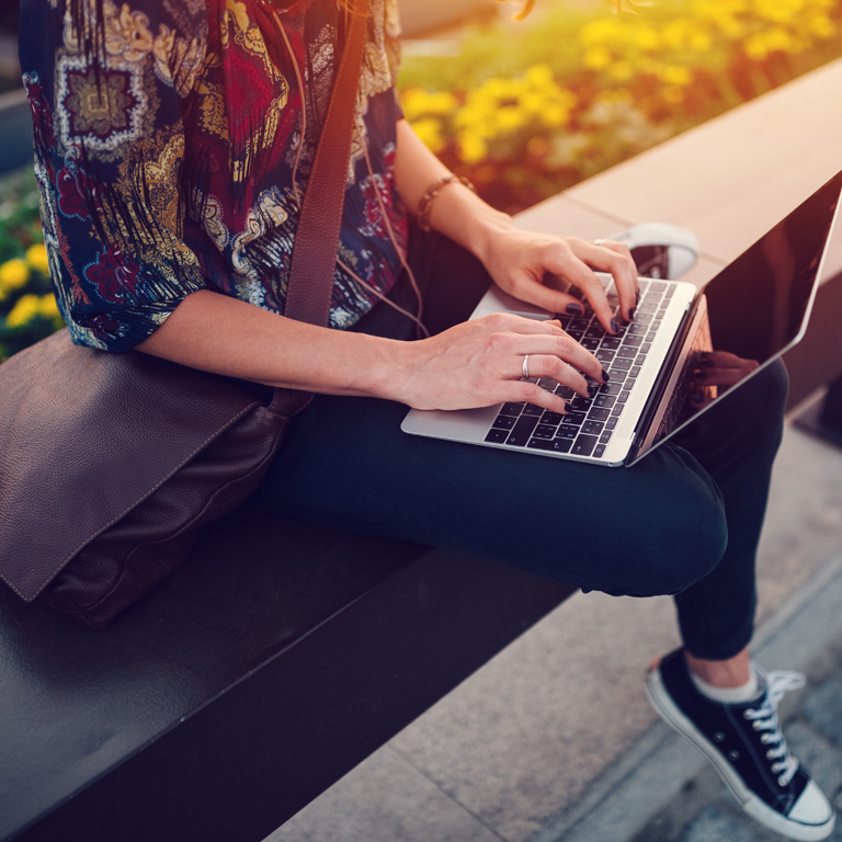 woman using laptop on bench
